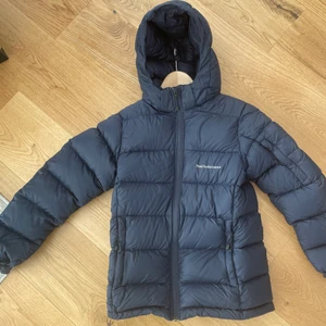 Peakperformance dunjacka - Tjock peak dunjacka i storlek 160. Mörkblå! Skada på ena ärmen som är lagad med textiltejp! Annars i bra skick. Frakt ingår