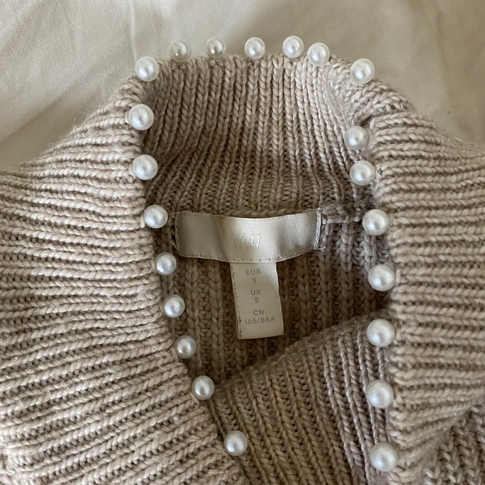 Säljer denna fina och högst oanvända stickade tröjan från H&M. Den har en liten polokrage med fina pärlor 🤍. Stickat.