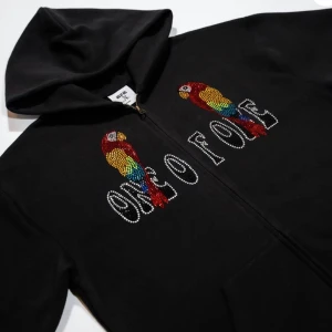Slutsåld One of One ”parrot” zip up hoodie - One of One zip up hoodie med rhinestones i size M, svart. Helt ny och aldrig uttagen ur lådan. Bud från 1100kr