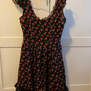 Cherry dress - Svart söt klänning med röda körsbär på, söta volanger på kanterna utav klänningen (bild 2). Inköpt hos Shock, tyvärr bara fått ligga i garderob & aldrig blivit använd. Storlek S. Frakten står jag för🌸