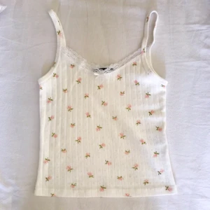 rare brandy melville floral skylar tank - deadstock/säljs ej längre vit floral lace skylar bow tank med pointelle pattern tyg. har bara tidigare sålts i usa. Köpt för drygt 400kr inkl frakt osv. passar xs-s (34-38). buda gärna (rimligt) ♡ 