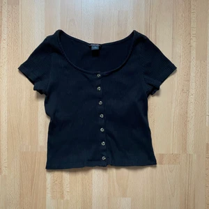 Svart ribbad t-shirt med knappar från MONKI  - Knappt använd asfin svart t-shirt från vårt käraste monki!😍jag är 162cm och brukar ha storleken XS-S och den sitter normalt på mig som referens! Kostade originellt 120kr