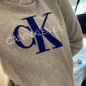 Calvin Klein hoodie - grå Calvin Klein hoodie med blåa detaljer. Köpt 2019 men aldrig använd så i nyskick. Storlek 14, passar mig som vanligtvis har S/M o är 168cm lång. Köparen står för frakten💕