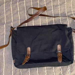 Axelväska med läderspännen - Jättefin, simpel svart tygväska med bruna läderspännen. Perfekt för den som vill fylla den med pins, eller för den som vill ha en vanlig enkel skolväska. Jag älskar den, men säljer den nu då min vita katt gör så jag inte kan ha svarta kläder längre hahaha. 120kr! 