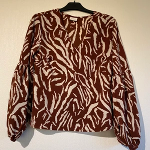 Blus från VILA - Spräcklig blus i brunt och vitt från VILA, storlek 44. Fluffiga ärmar.