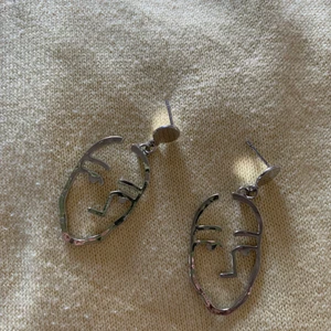 Silvriga örhängen - Silvriga örhängen som är formade som ansikten. Medelstora. 