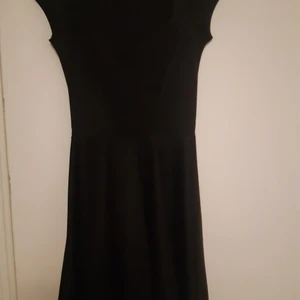 Boohoo Klänning  - En enkel svart klänning från boohoo. Töjbart material... känns lite 50s inspired 🤔 Formar brösten 🤤 Halvlång, inte 50tals lång men heller inte föör kort. Svängig. Kortärmad. Använd en gång för en photoshoot 💗 Köparen står för alla fraktkostnader. Fråga inte hur den ser ut på mig, vill ej synas på bild.