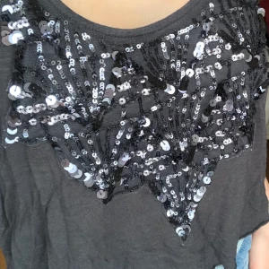 Hollister  - Ett grått linne från hollister med paljetter där fram lite lite kroppat inte använd mycket pågrund av inte kommit till användning så därav fint skick