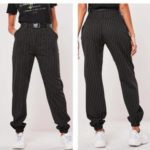 Missguided Black Pinstripe Cuffed Cargo Trousers. - EU storlek: 36. Jättefina byxor som är formfitting vid midjan och rumpan och lite lösare längst benen🍑 Kommer med bälte! Använd endast en gång, dock är i helt ny skick. 💎