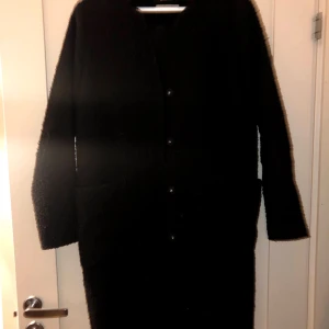 Svart kappa  - Svart kappa med lite ull i, 2 fickor, knäppning med knappar. 