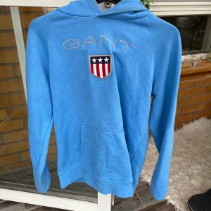 Gant hoddie  - Ljusblå Gant hoddie i storlek 176, passar mig som är S och då sitter den lite löst. Kan mötas upp i Helsingborg/Båstad. Annars kan jag frakta men står ej för kostanden. Endast swich. Startbud 200 kr, buda i kommentarerna. 🤎