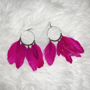 Örhängen med rosa fjädrar  - Guld färgade örhängen med rosa/lila fjädrar. Kan skicka flera bilder via meddelanden.