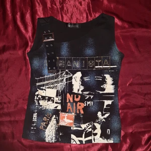 Topp - Punkig topp med print och bältesliknande axelrem. Fint skick. Kan mötas upp i Stockholm, annars står köpare för frakten :)