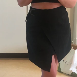 Omlottkjol CARIN WESTER - Svart lite ribbad Kjol med brunt spänne. Aldrig använd 