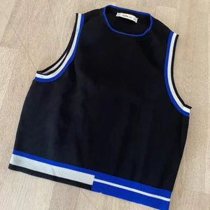 Blå/svart kort topp - Svart kort topp med blå och vita detaljer! Sitter väldigt snyggt på och passar både till fest och vardag! Köpt på Zara i storlek M. Köparen står för frakten!