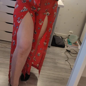 Blommiga röda byxor - Unika byxor med slits framtill på båda benen. Byxorna sitter uppe med resår, men har ett ett band som fin detalj. Aldrig använda, lapparna sitter kvar. Köpare står för frakt ❤️❤️