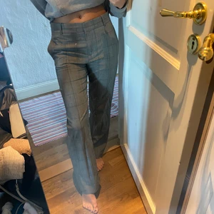 Gråa utsvängda kostymbyxor - Säljer mina jättesnygga och sköna kostym byxor från & orgel stories, gråa med gröna inslag! Super snygga i storlek 34, men funkar till 36!! köpte för 900kr.