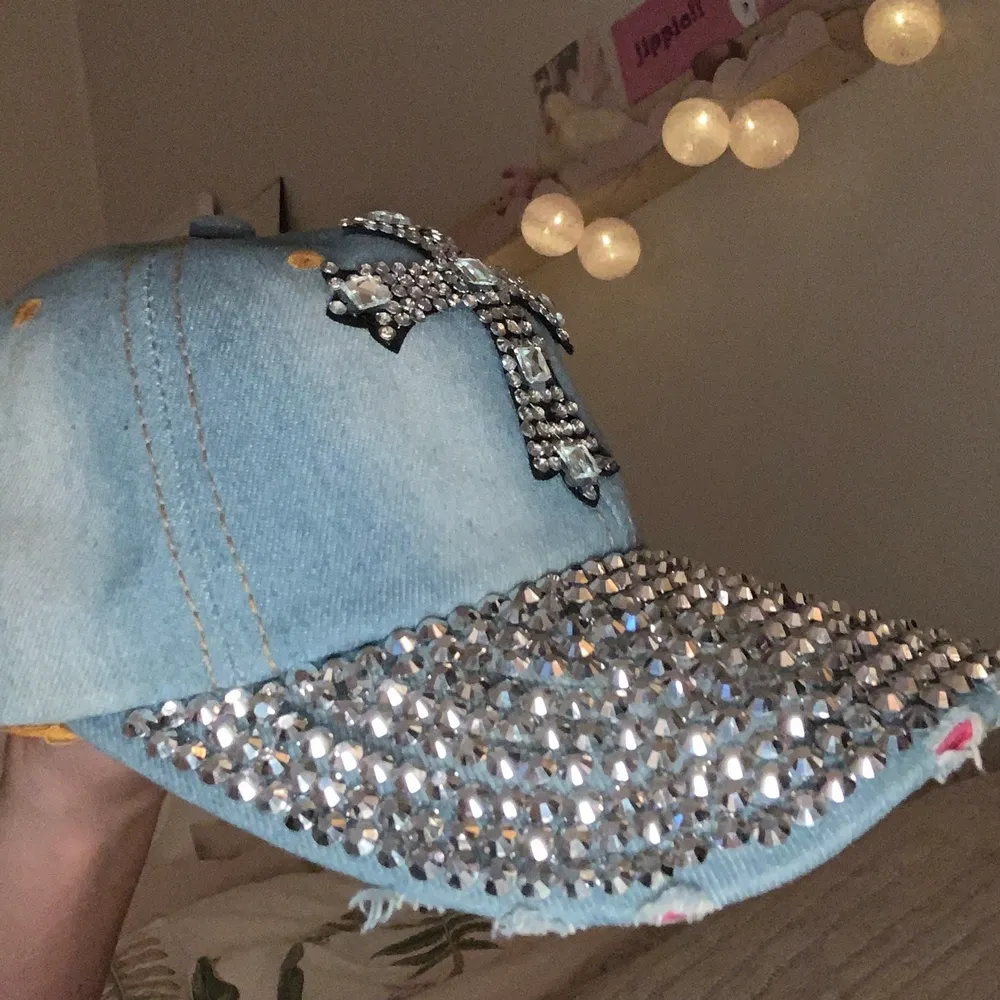 Blå jeans keps med rhinestones på och ett kors av rhinestones. Den är riven längst fram med rosa under.. Accessoarer.