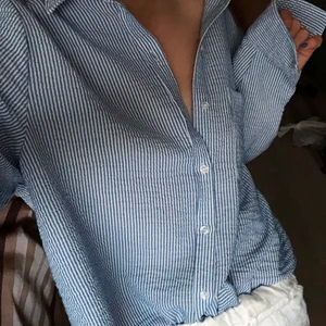 Randig skjorta - Blå-vit randig skjorta med knytning längst ned. I bra skick - frakten är inräknad i priset, kan även mötas upp i Stockholm.