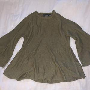 En VILA tröja som är militärgrön och ganska tjockt material. Lite kortare ärmar som är breda och tröjan är formad som en kjol typ.