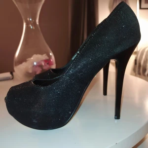 Perfekta nyårsklackarna, 38 - Svarta, öppen tå och ca 2 cm platå. Skimrande/glittriga. Perfekt till festen! Nyskick! 
