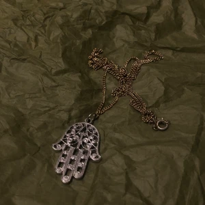 Silver halsband  - Ett silvrigt halsband med en hand på. Det är i bra skick då det inte används så mycket. Säljer då det inte används. Vid intresse skriv privat. Frakten ingår inte i priset.
