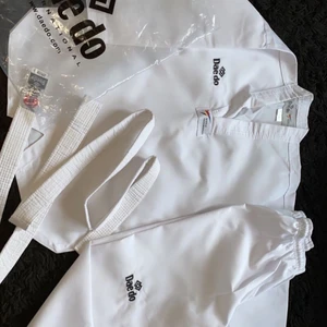 Taekwondo kläder  - Det här är taekwondo kläder, de är helt friska från smuts eller skador. Dessa är endast använda 3-4 gånger. De är i storlek 150 så passar en kanske liten tjej/kille  runt 9-12 år beroende på storleken. De följer med ett bälte med taekwondo tryck på. De är köpta för 1000 kr men säljer för 600 kr. 