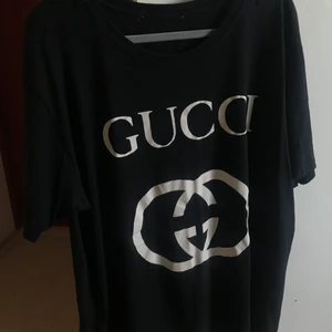 Svart Gucci T-shirt - Säljer en äkta Gucci T-shirt i oversized modell som är inköpt för några år sedan, har därför inget kvitto kvar. Den har använts flitigt, lappen i nacken har tyvärr trillat av, men t-shirten är i fint skick. Passar både killar och tjejer. Köparen står för frakten. 
