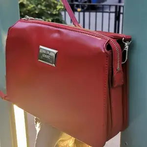 Lyxig röd väska i utmärkt skick, läder, original, kommer med nyckelring. Perfekt för vardagen eller en festlig outfit. Jag kan träffas i Täby C.