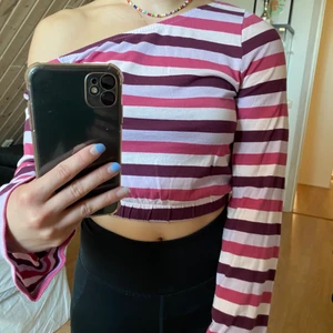 One shoulder topp - Randig topp i rosa och lila, lite kortare modell med resor nertill och vida ärmar. I skick som ny! Hör av er vid frågor eller om ni vill ha fler bilder!💞