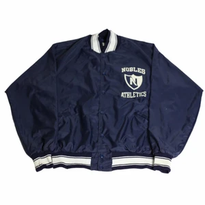 Nobles University - En riktigt fet marinblå jacka som har fräscha vita detaljer och är perfekt som en höstjacka där man vill  få till en lite nittiotalsskänsla som är så svår att få tag på. Är gjord av nylon och är i väldigt gott skick. Är troligtvis gjort i USA och den är även thriftad där.