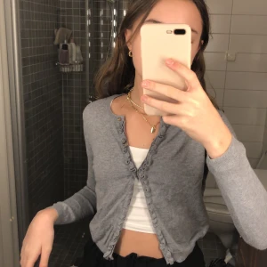 Kofta - Säljer min super fina kofta då den börjar bli för liten, tröjan sitter super fint och har en fin volang i mitten, super inne just nu, budet startar på 100kr