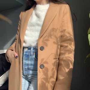 Zara kappa storlek XS - en superfin beige/kamelfärgad kappa i kavajstil från zara! den är i fint skick förutom att sömmen har gått upp i den ena fickan, men det är inget som syns och är lätt att laga. längd: 94 cm. ärmlängd: 62 cm. ytterfodret innehåller 58% ull🤍