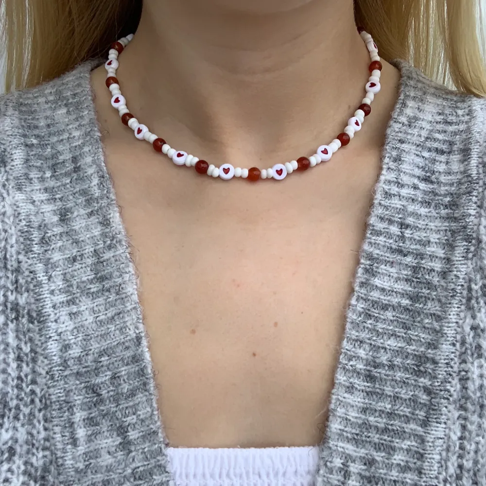 Vitt pärlhalsband med röda hjärtan och röd/orangea pärlor❤️🧡🤍 halsbandet försluts med lås och tråden är elastisk . Accessoarer.