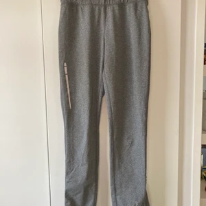 Träningsbyxor med ficka  - Snygga byxor med ficka i grå färg. Fickan går att stänga och har sladdhål om man fortfarande använder vanliga hörlurar
