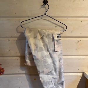 Adidas cargo pants - Adidas cargo pants i vitt/rosa camo. Stora i modellen men passar S/M, storleken är 36. Jättefina på, fint skick, köpta förra året men endast testade. Möts upp i Stockholm eller norrtälje. Eller du står för frakten 😇