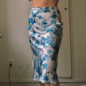 Satin kjol i vitt/blått baktik  - Midi/maxi kjol i satin imitation med coolt blått mönster. Materialet känns super lyxigt. Dragkedja i bak som inte syns. Nyskick. Mitt midjemått är 28cm❤️❤️