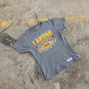 LAKERS TEE!! 💛💜 - T-shirt producerad av de anrika Mitchell & Ness åt Nba-laget Los Angeles Lakers. Tröjan är i grymt skick, trycket är dock lite slitet men det är inget som stör helheten av tröjan. riktigt najs t-shirt till sommaren. Tröjan är S men skulle snarare säga att det är en Xs. Det är bara att skriva om du undrar något! 💛💜