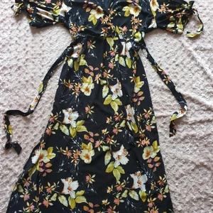 Blommig maxiklänning  - Blommig maxiklänning med ca 40 cm slits på båda sidor, trekvarts ärm med knyte så man kan visa hud på armarna om man vill- se bild. Använd en gång.