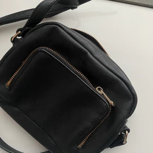 Väska svart - Axelremsväska med flertalet praktiska fack. Får plats med vardagliga nödvändigheter utan problem. Mycket bra skick. Exklusive frakt