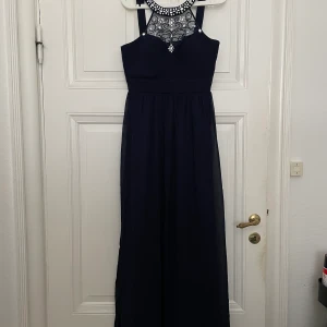 Söt balklänning   - En superfin balklänning i mörkblå med detaljer runt halsen. Köpt från Bubbleroom. Endast använd en gång på min studentbal. Snygg utan halsband, med uppsatt hår och silver-örhängen✨ Storlek 38/40. Hör av er om ni vill ha mer information, bilder, eller mått 😊 Gratis frakt! 