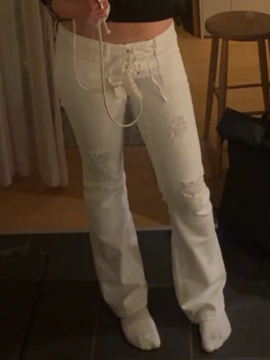 Vita bootcut jeans med snörning - Säljer pga dem är för stora för mig, skit snygga använda några gånger. Är i tall storleken, är 177 och dem ör bra i längd 