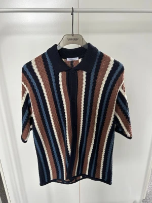 Randig stickad Piké   - Snygg stickad skjorta från Knowledge Cotton  vertikala ränder i marinblått, brunt, beige och vitt. Aldrig använd. Storlek M. Köpt för 1299. 