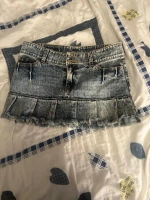 Jeanskjol med volang och fransad kant - Cool jeanskjol från Replay i blå denim med volangdetalj och fransad nederkant. Kjolen har klassiska fickor fram och bak samt bälteshällor. Perfekt för dig som gillar en trendig och avslappnad stil.