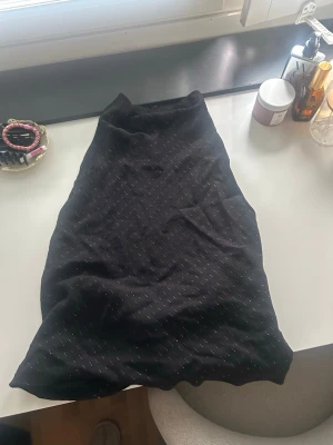 Svart topp med guldiga detaljer från Zara - Snygg svart topp från Zara med diskreta guldiga detaljer som ger en glittrig känsla. Toppen har en rak och enkel form, perfekt för att styla med olika underdelar Materialet känns mjukt och följsamt mot kroppen.