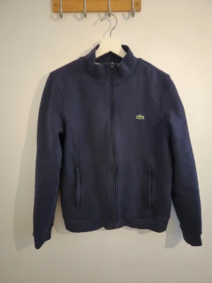 Mörkblå ziptröja från Lacoste - Snygg mörkblå jacka från Lacoste i mycket gott skick som ny.