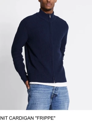 Mörkblå stickad cardigan med dragkedja - Mörkblå stickad cardigan från FRIPPE med hög krage och hel dragkedja framtill. Tröjan har en ribbad struktur och är perfekt för lager-på-lager. Passar till både jeans och chinos för en avslappnad men stilren look.