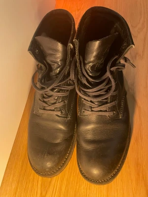 Red Wing Beckman Round 9014 Black Featherstone Leather - Klassiska Red Wing boots av mycket hög kvalitet.  Väldigt mycket liv kvar. Storlek 40 men jag har 41-42 och tog denna storlek för att forma efter fötterna. Skulle säga att dom funkar för både 40 och 41-42