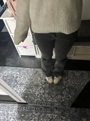 Mörkgrå bootcut jeans - Säljer ett par mörkgrå jeans med bootcut passform. Jeansen har klassisk femficksdesign, låg midja och är tillverkade i mjukt denimtyg. Perfekta för dig som gillar en avslappnad men ändå snygg design. Lappen är avklippt och de är köpta här på plick så jag vet ej vart de är ifrån hål vid knäna och en av skärp-ögglorna har lossnat men syns inte
