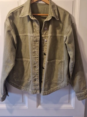 Olivgrön jeansjacka från Zara XS - Snygg olivgrön jeansjacka från Zara i storlek XS. Klassisk modell med krage, två stora fickor framtill och knäppning med metallknappar. Perfekt att slänga över en hoodie eller t-shirt för en avslappnad look.